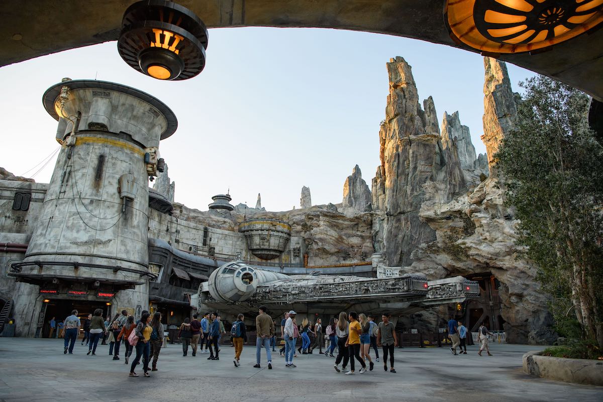 Guests explore Star Wars Galaxys Edge with the Millennium Falcon in the background