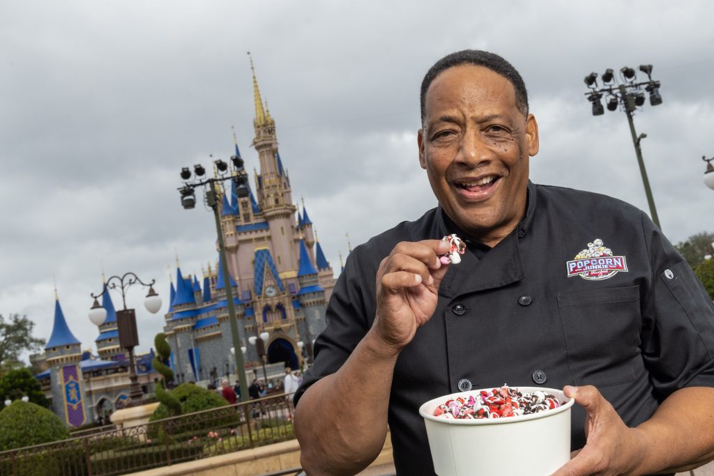 Neal Crosier, co-founder of Popcorn Junkie samples specialty popcorn in front of Cinderella Castle