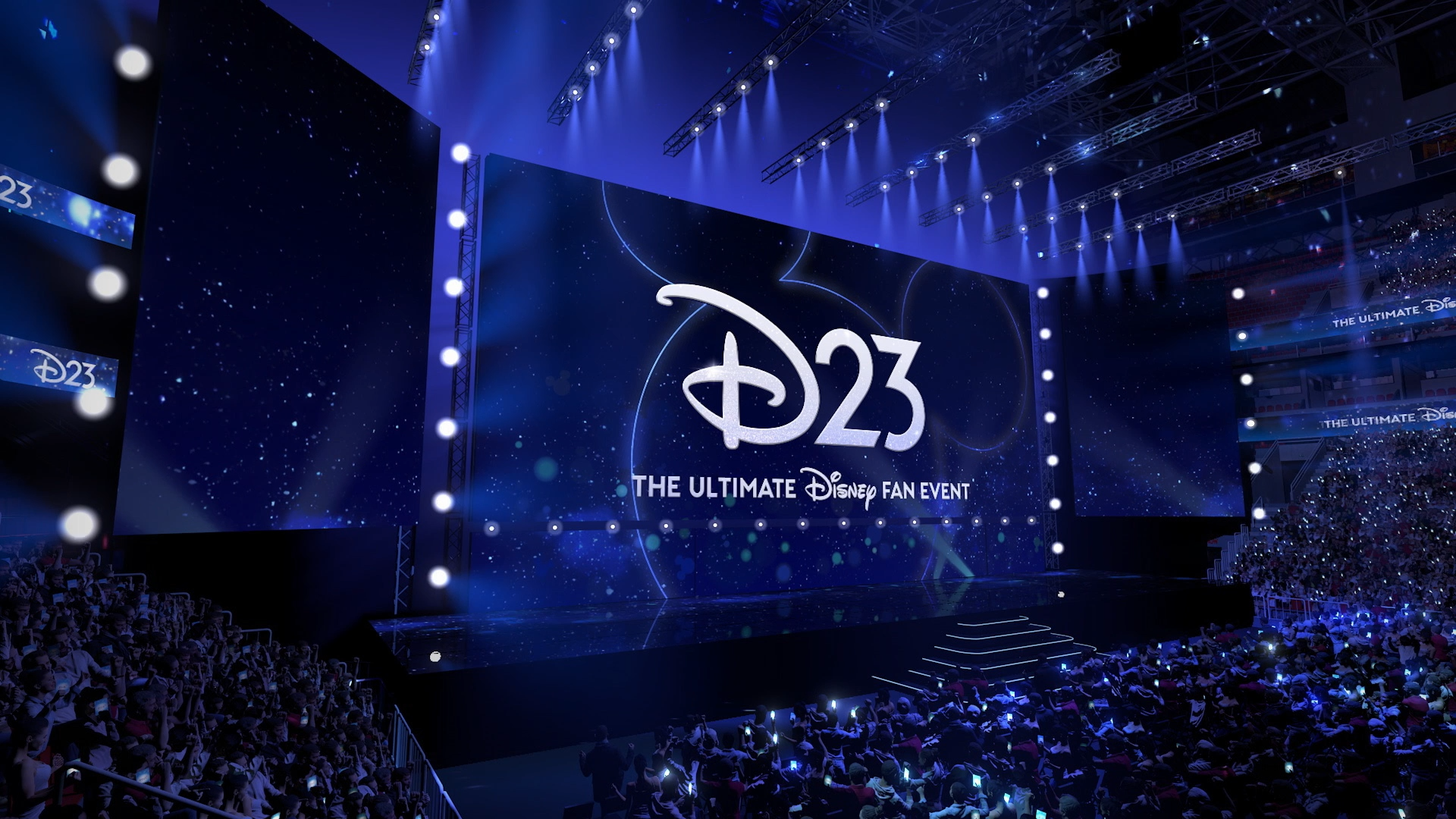 The stage of the Honda Center with the words "D23 The Ultimate Disney Fan Event" on the screen in front of a packed auditorium of guests.