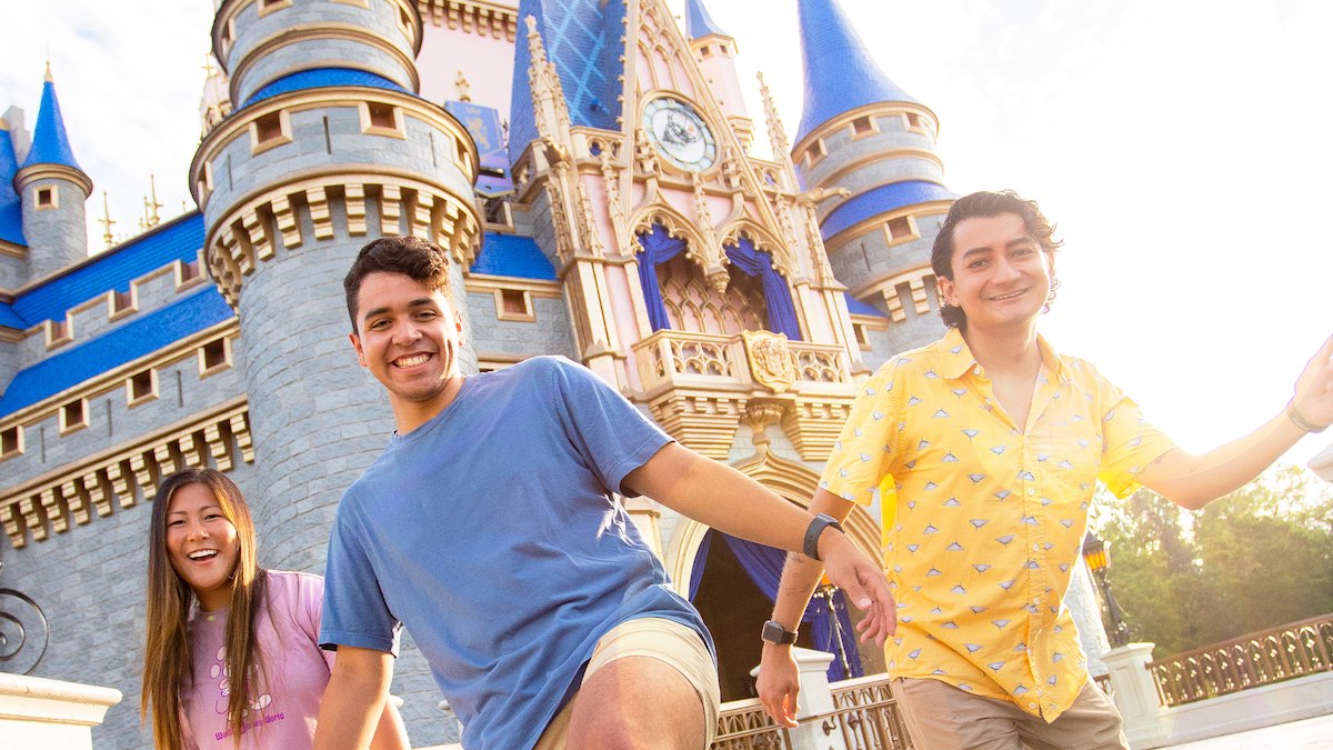 Two young men and a young woman in front of Cinderella Castle at Magic Kingdom.