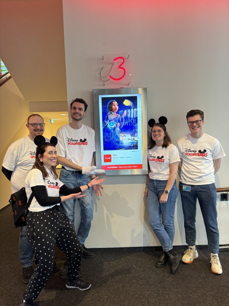 Five Disney VoluntEARS in front of the movie posted for "Wish."