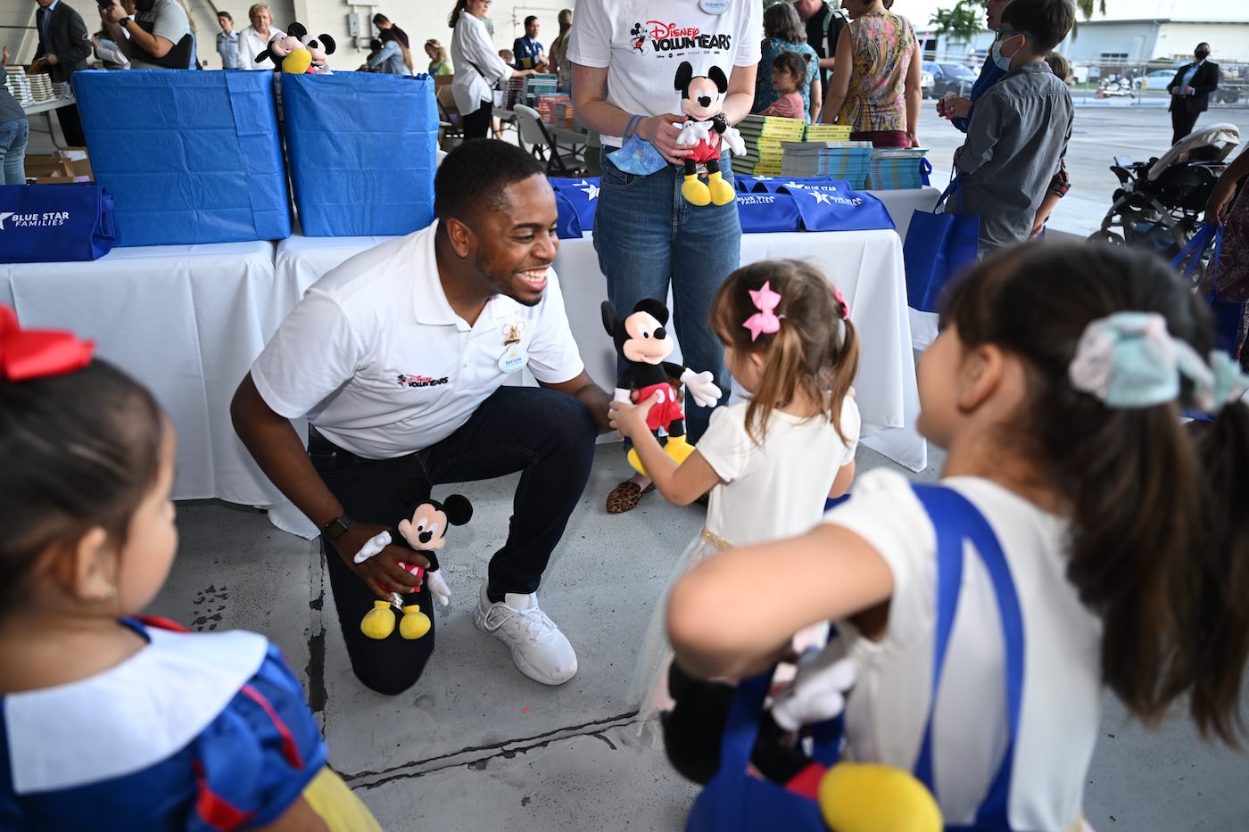 Disney VoluntEARS providing children with plush Mickey Mouse toys and books.