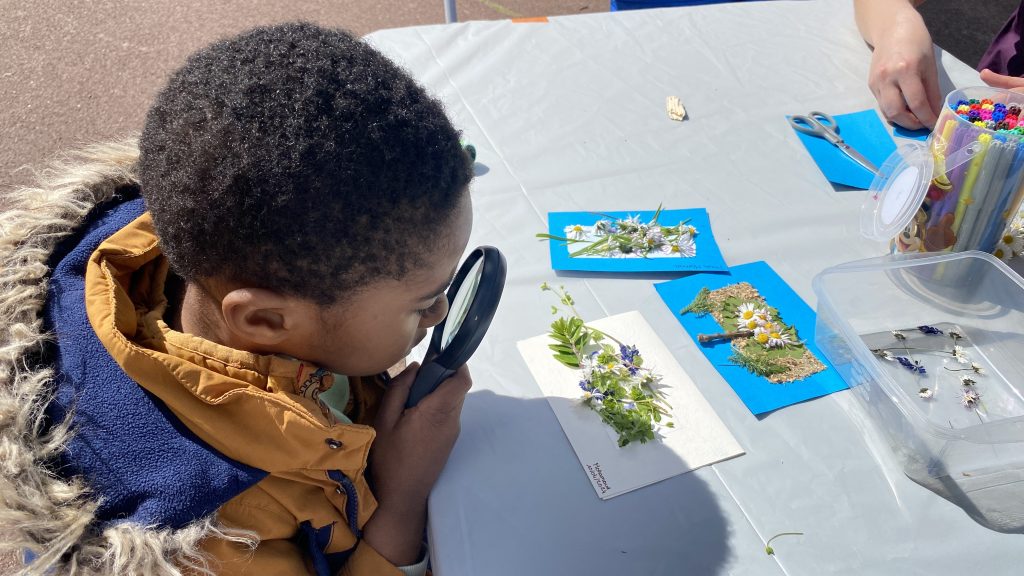 Child looks through magnifying glass during nature workshop