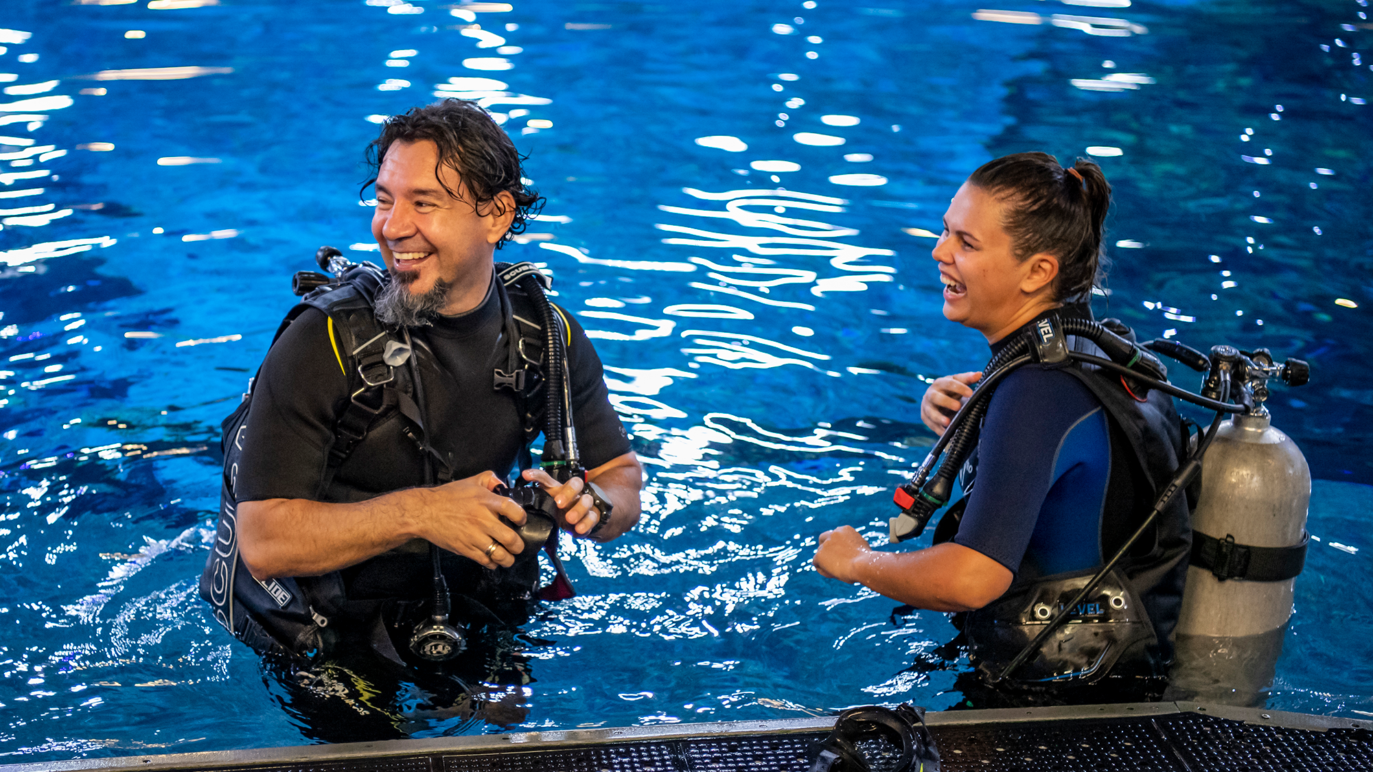 Two cast members in EPCOT aquarium tanks laughing