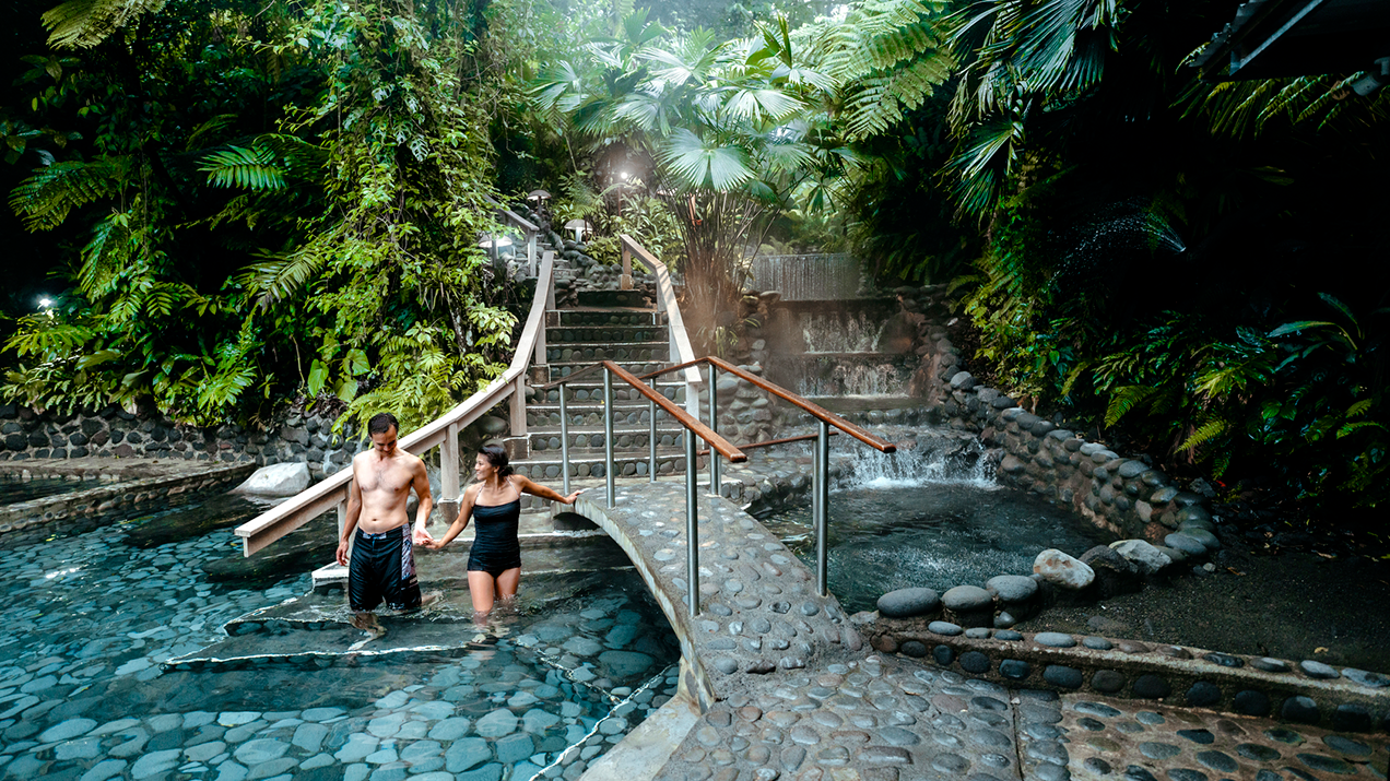 Couple walking into a natural pool in tropical environment