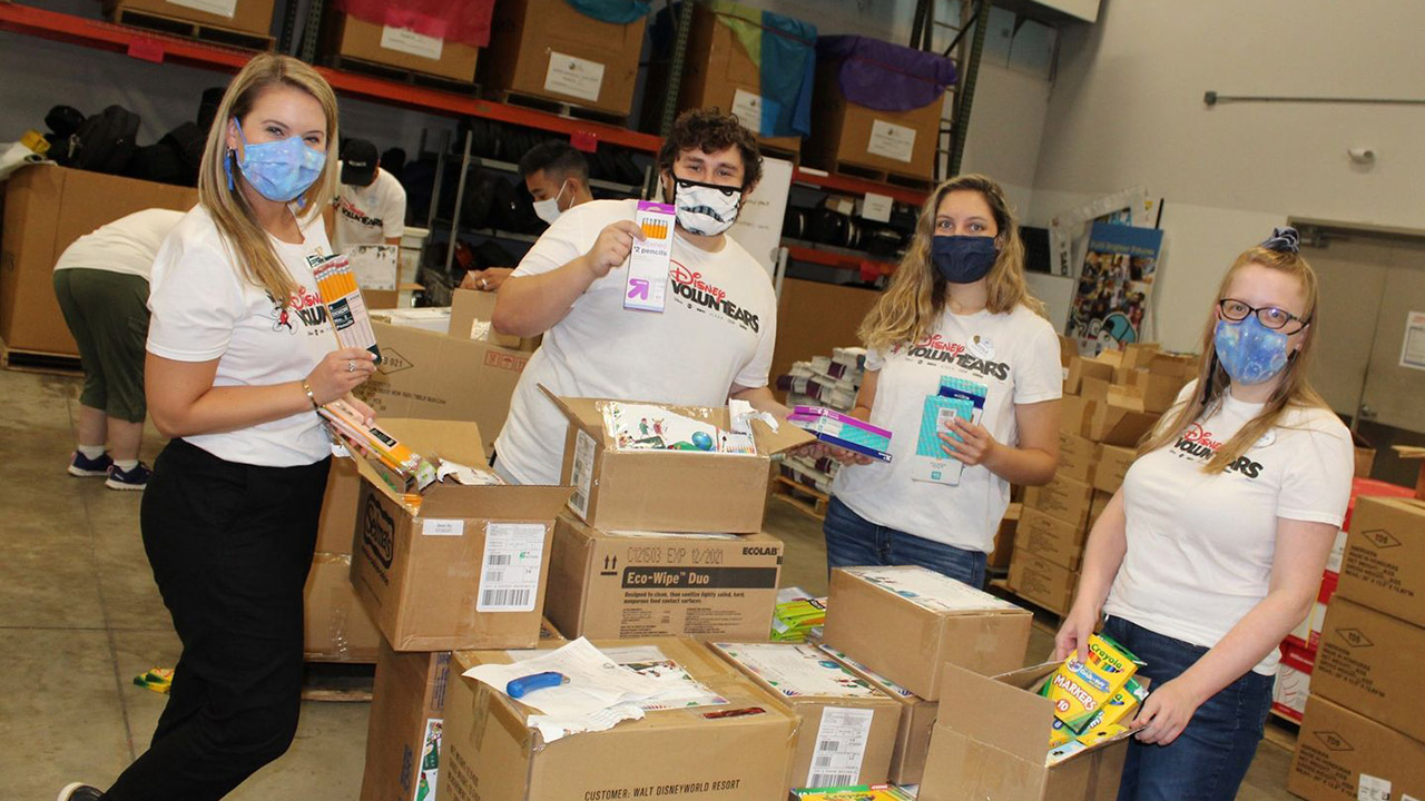 Disney VoluntEARS are sorting school supplies into boxes for a local community activity.