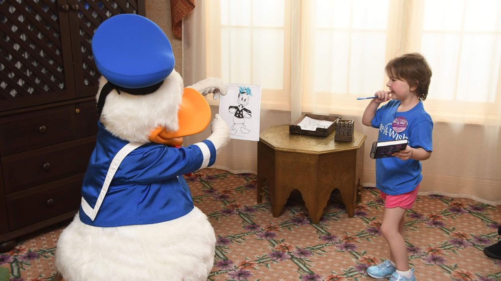 Donald Duck interacts with a child visiting Disney on a wish trip from Make-A-Wish.