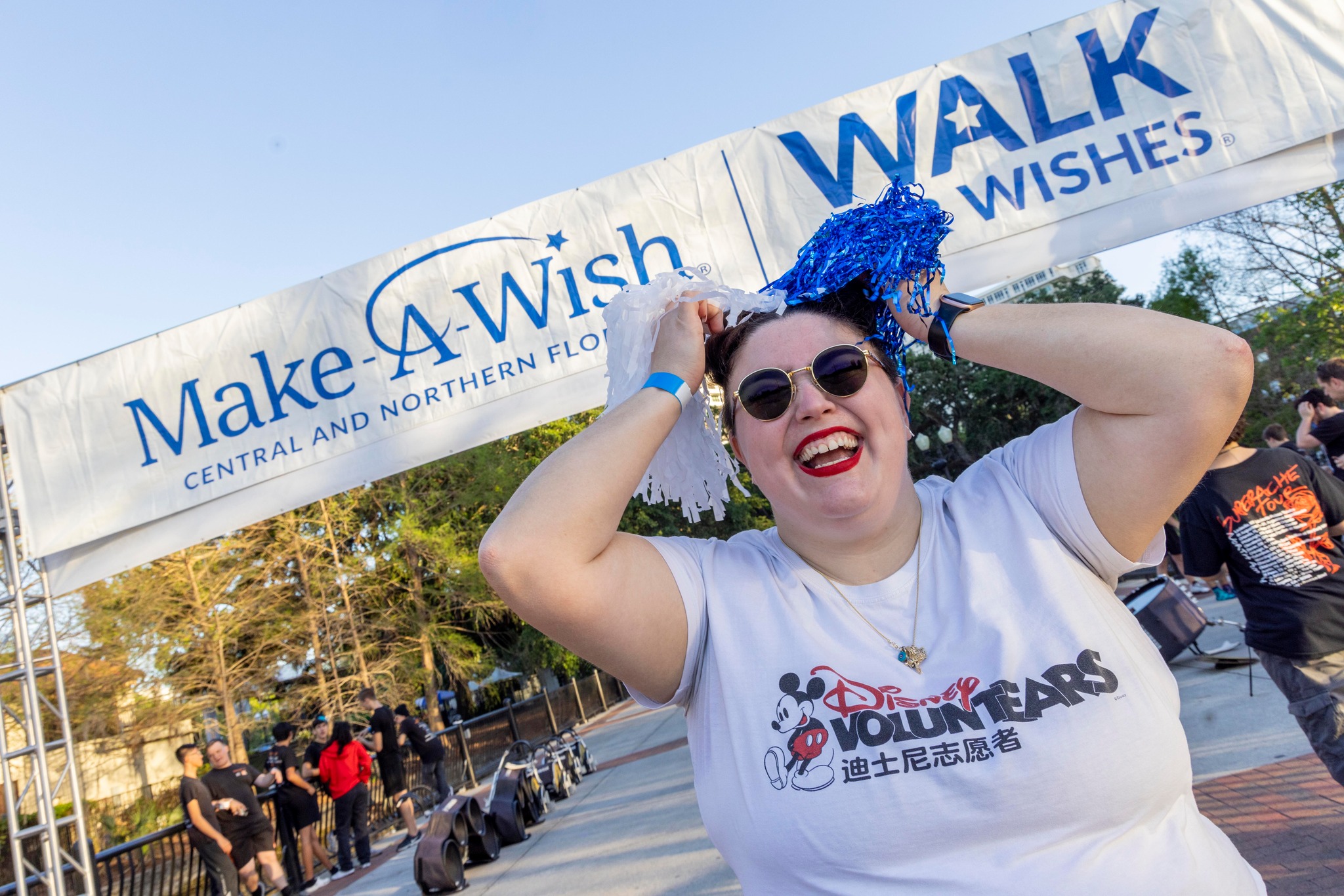 Disney cast member standing underneath a Make-A-Wish and Walk for Wishes banner at the start line