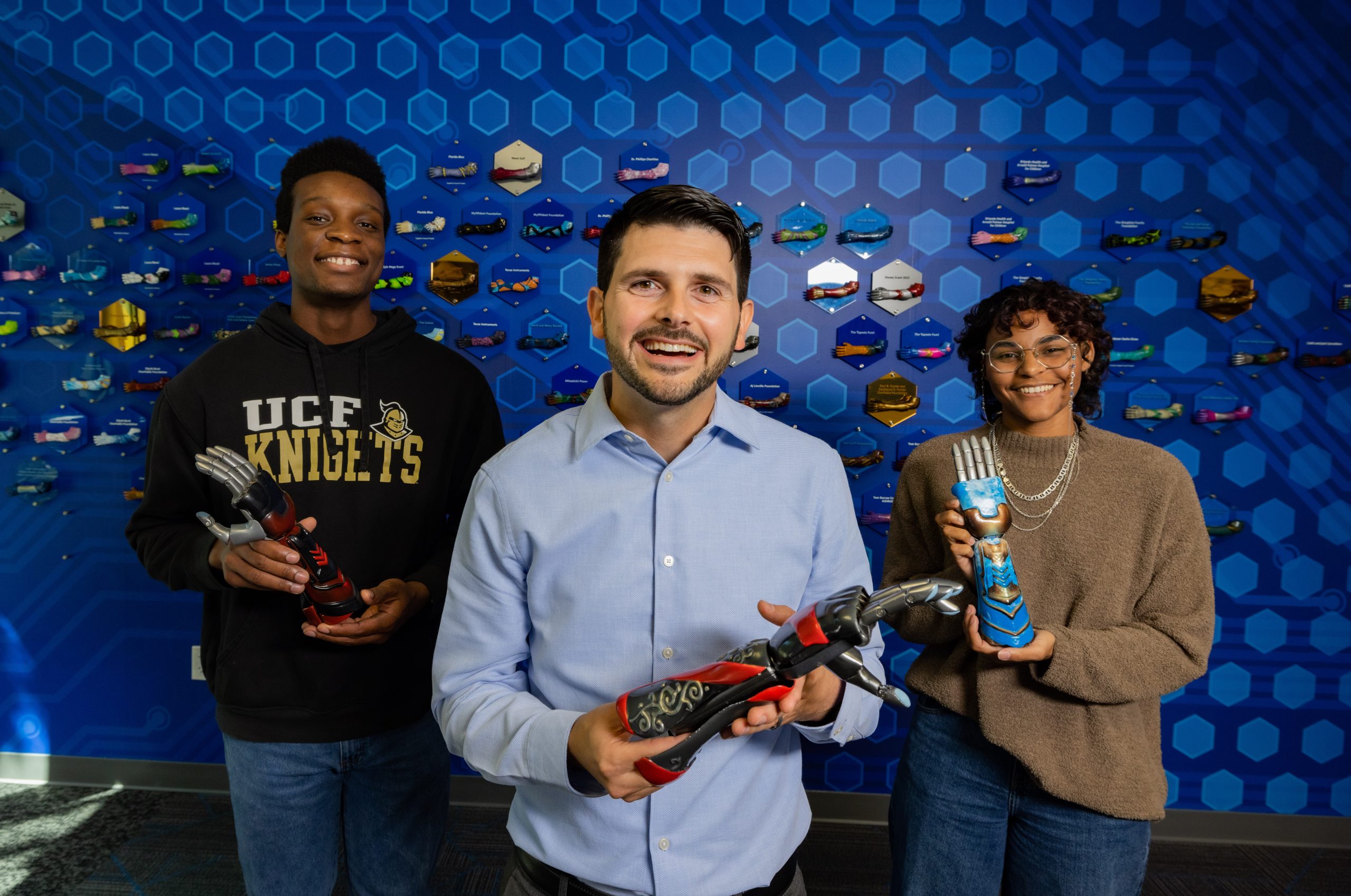 Owner, Albert Manero and two University of Central Florida students proudly display bionic arms.