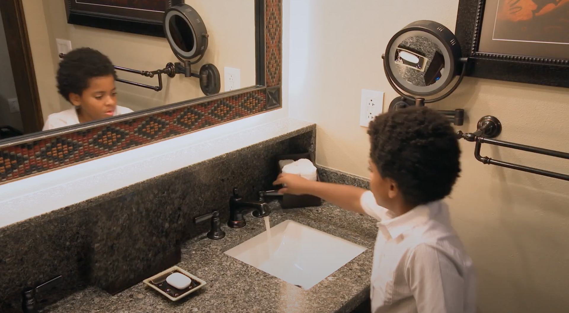 A child turning off the bathroom faucet at a Walt Disney World resort.