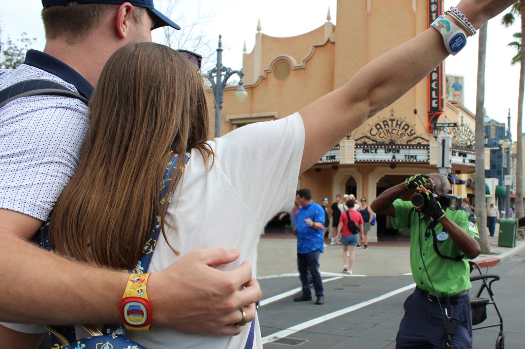 Disney PhotoPass cast member taking a photo of two people at Disney's Hollywood Studios.