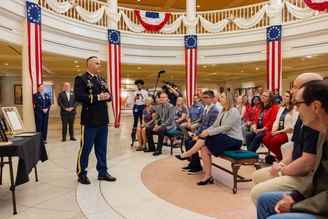 Man in military uniform speaking to people gathered in The American Adventure