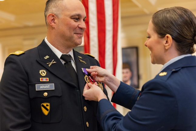 Man in military uniform receiving Purple Heart award from woman in military uniform
