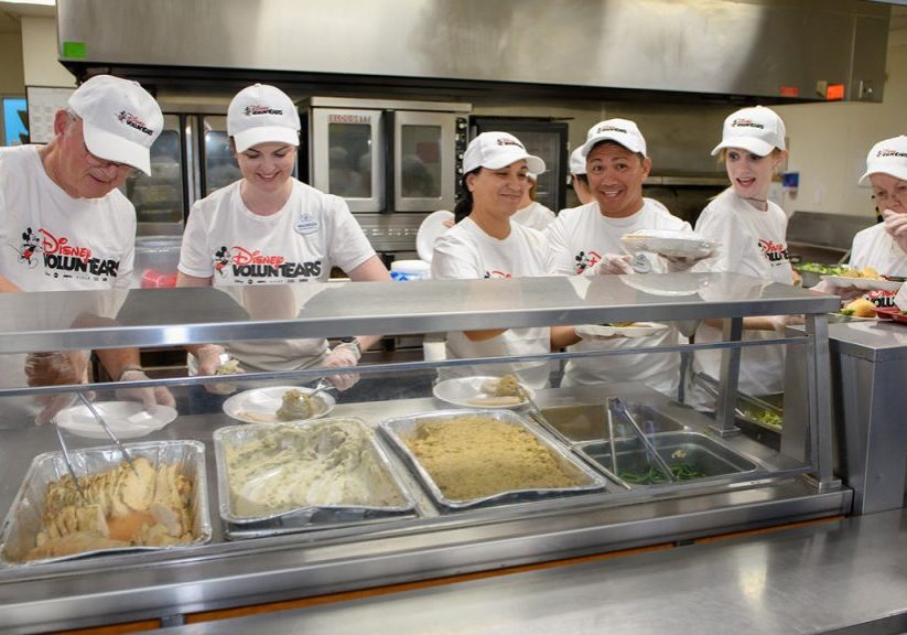 Disney VoluntEARS are seen serving meals in a kitchen at the Coalition for the Homeless of Central Florida.