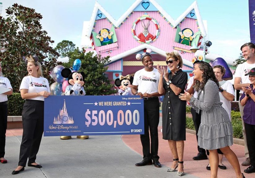 Disney VoluntEARS and Cast Members are gathered at Give Kids the World Village for a Disney Grant presentation during the 50th Anniversary of Walt Disney World Resort.