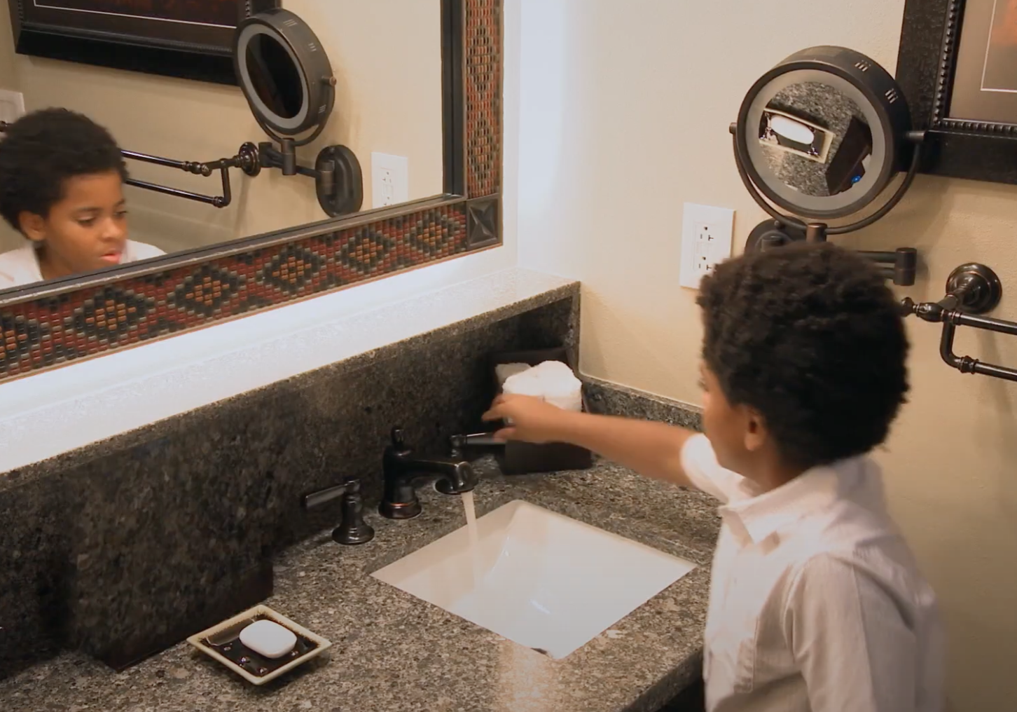 A child turning off the bathroom faucet at a Walt Disney World resort.