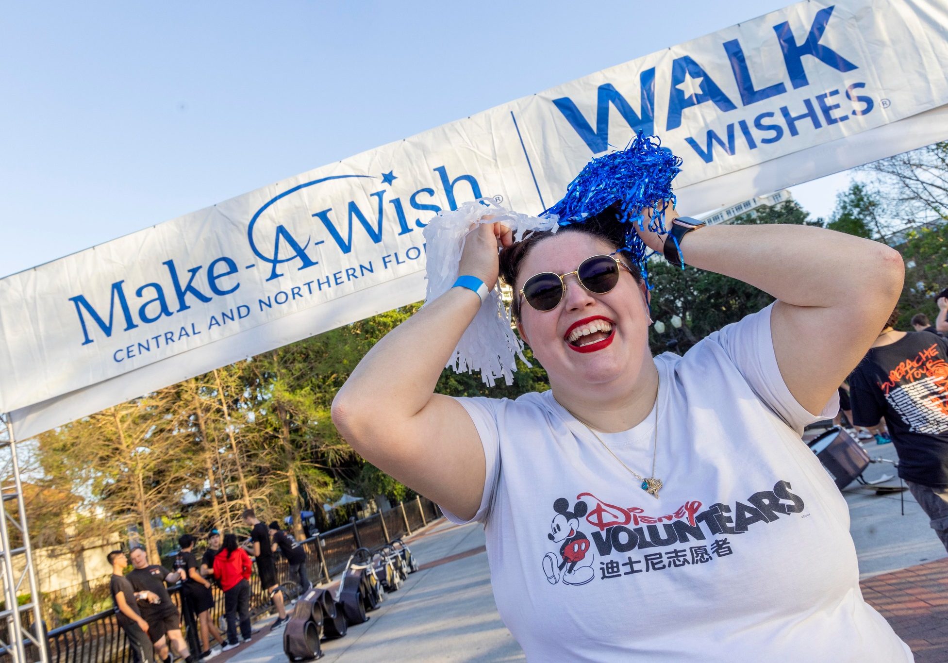Disney cast member standing underneath a Make-A-Wish and Walk for Wishes banner at the start line