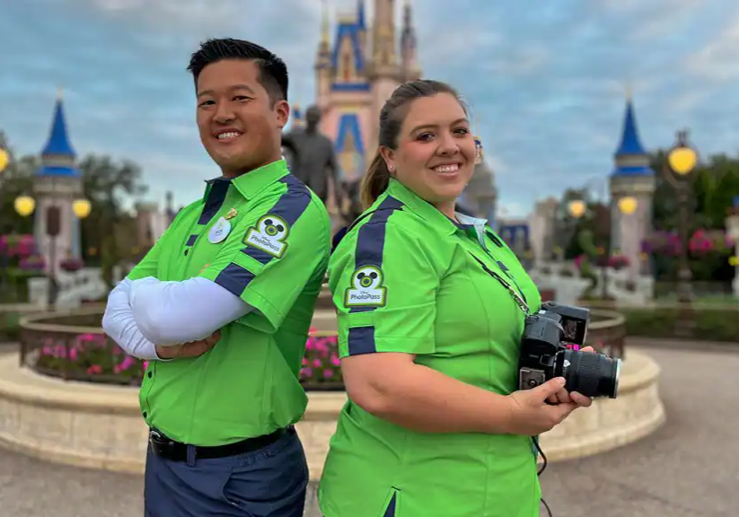 Two Disney PhotoPass cast members back-to-back in front of Cinderella’s castle.