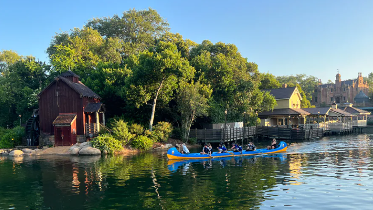 Cast Members in a blue canoe as the sun rises on the Rivers of America.