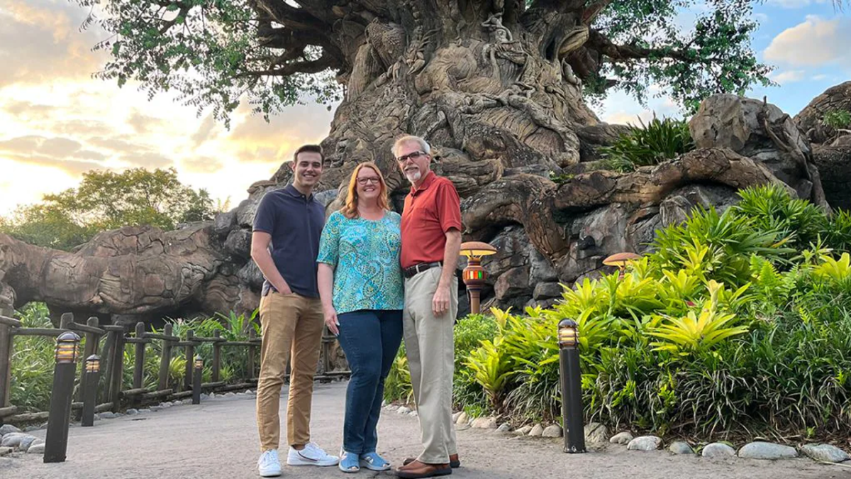 Son, mom and dad, all Cast Members, standing together in front of the Tree of Life.