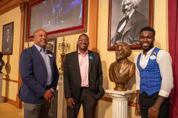 Three Cast Members pose in the Lincoln Theater, featuring a new installation honoring slavery abolitionist leader Frederick Douglass.