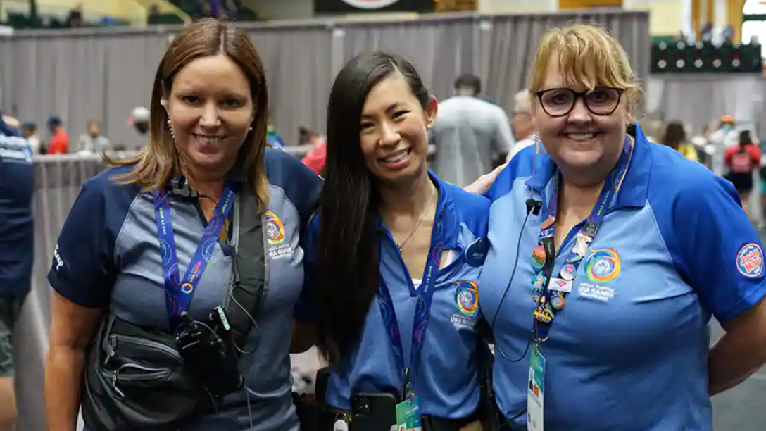Three Cast Members pose for a picture wearing Special Olympic shirts and lanyards.