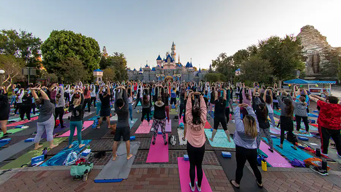 Hundreds of Cast Members doing yoga in front of Sleeping Beauty Castle at Disneyland Resort.
