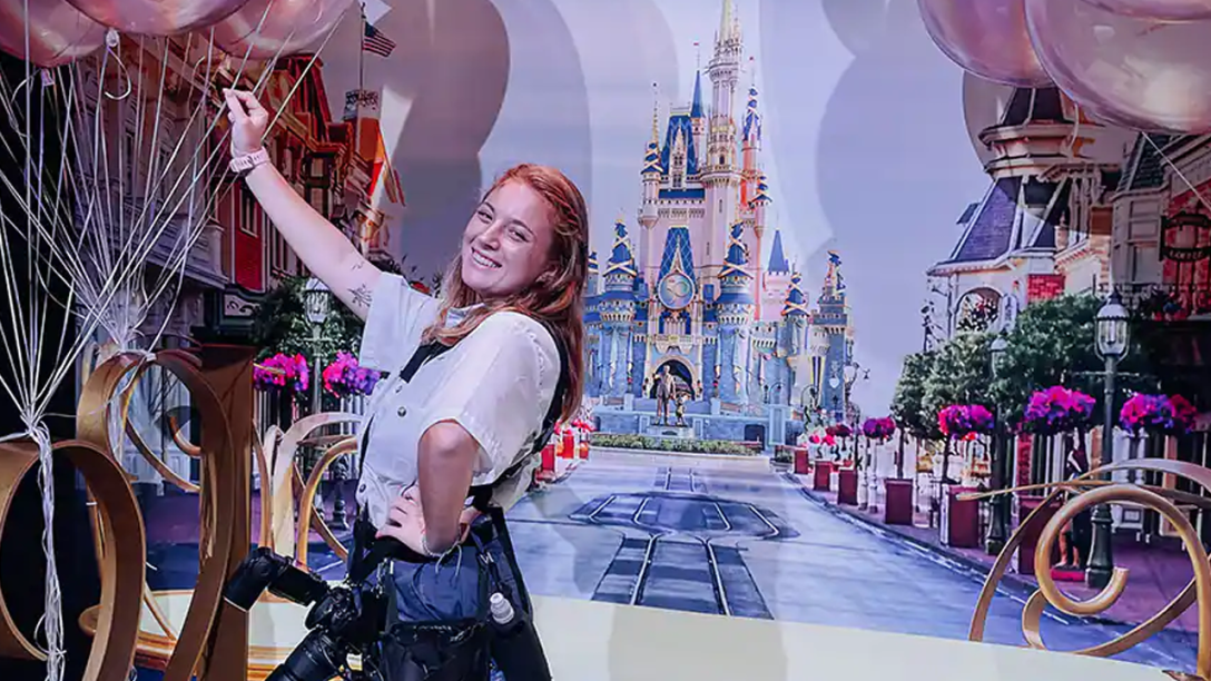 Female Photopass Cast Member posting with a Cinderella Castle backdrop and balloons.