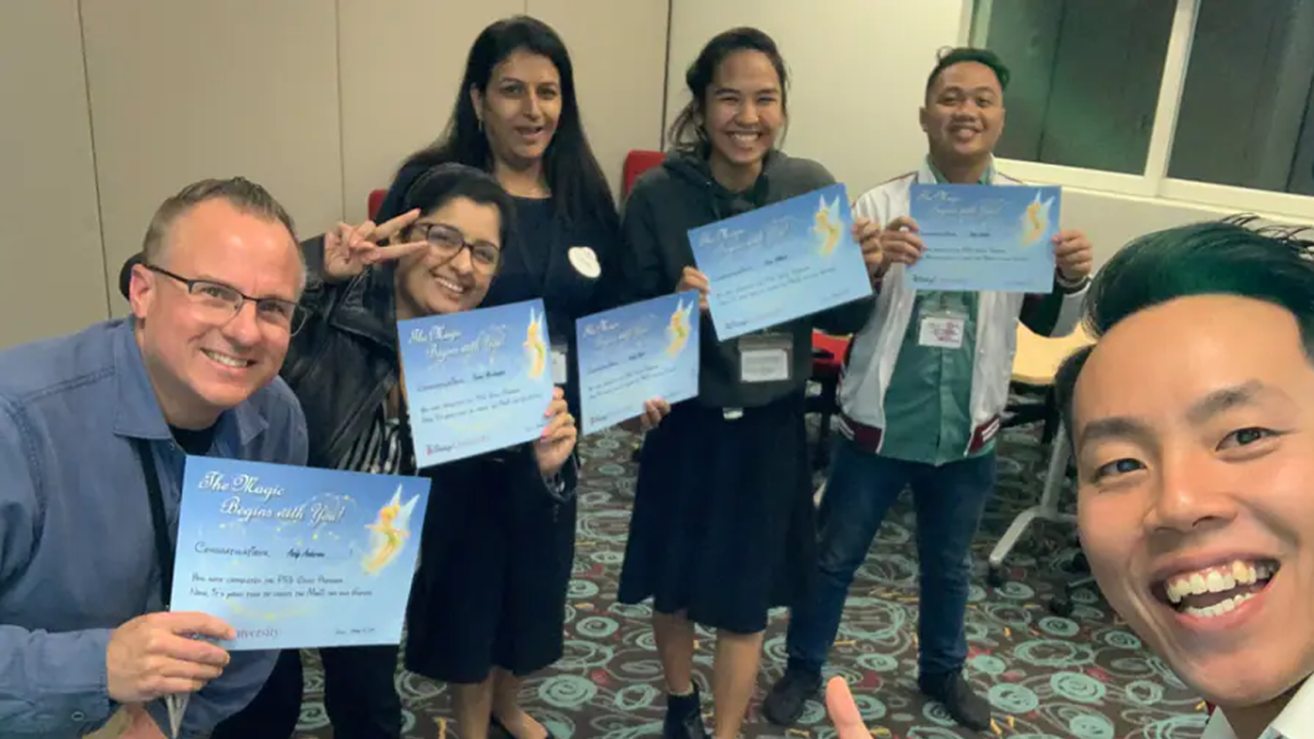 Six Hong Kong Disneyland Cast Members pose for a selfie with award certificates.
