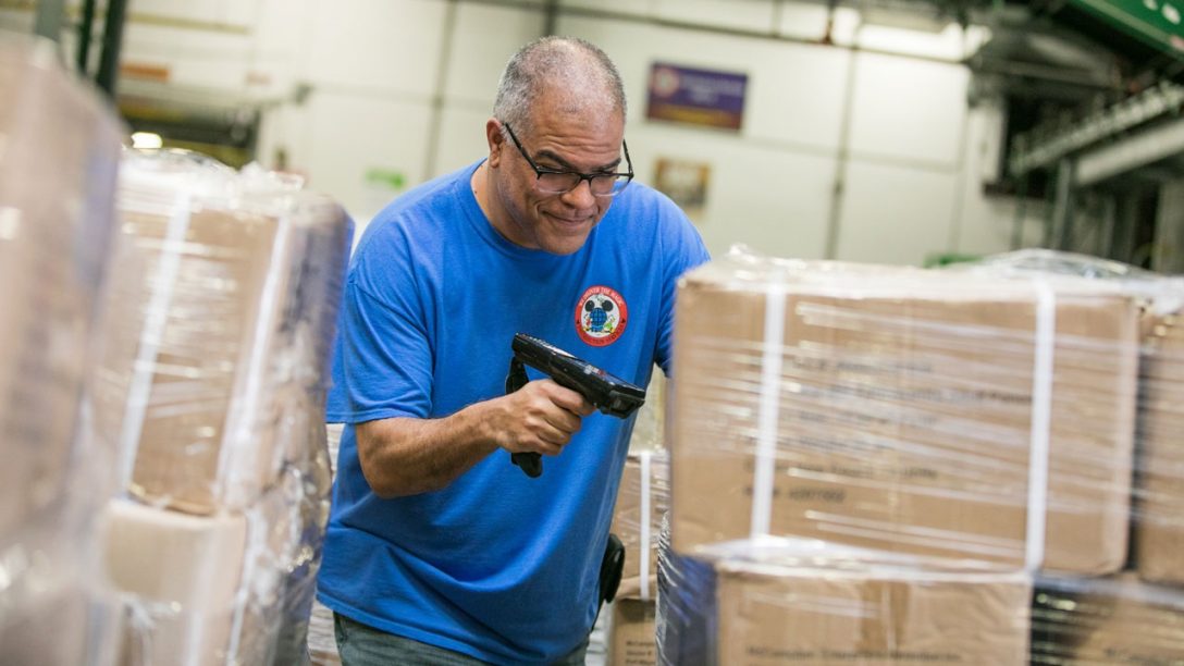 Disney Warehouse Cast Member scans boxes of masks to be shipped.
