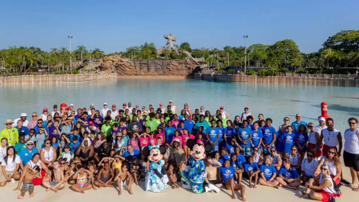 Children gather at the Typhoon Lagoon wave pool with Minnie and Mickey and Randy Moss to take a group photo of the World's Largest Swimming Lesson.