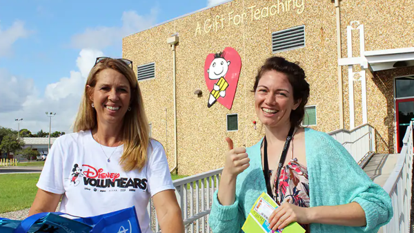 Disney VoluntEAR posts for a picture with a Gift for Teaching representative outside of the building. 