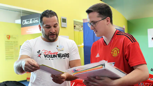 Disney VoluntEAR looks over a school supplies list with a teacher at a Gift for Teaching. 