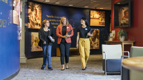 Jennifer walking through the hall at Disney University with two female coworkers.