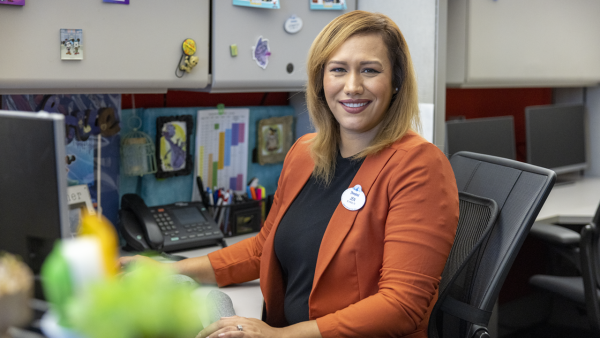 Jennifer wearing a red blazer sitting at her desk. 