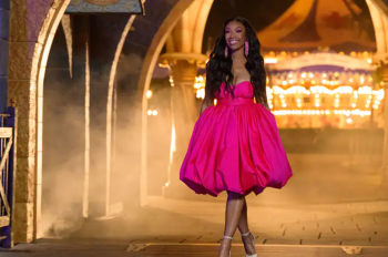 Global superstar and Grammy Award-winning recording artist Brandy walking through the archway of Sleeping Beauty Castle in a pink dress at night.