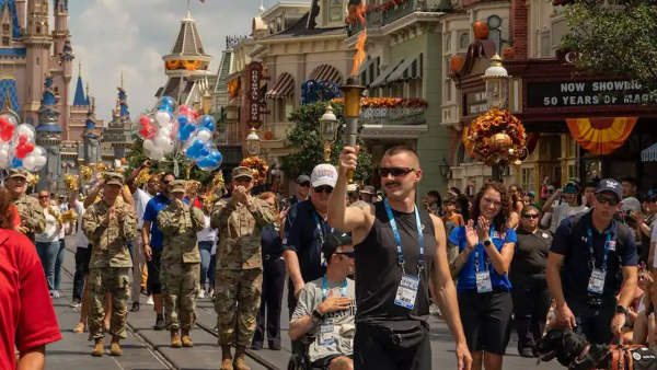 Veterans parading down Main Street USA carrying a torch and red, white and blue balloons. 