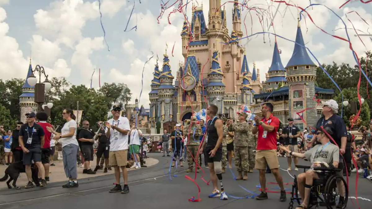 Veterans participating in a parade in front of Cinderella Castle with red, white and blue streamers flying.
