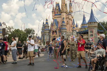 Veterans participating in a parade in front of Cinderella Castle with red, white and blue streamers flying.