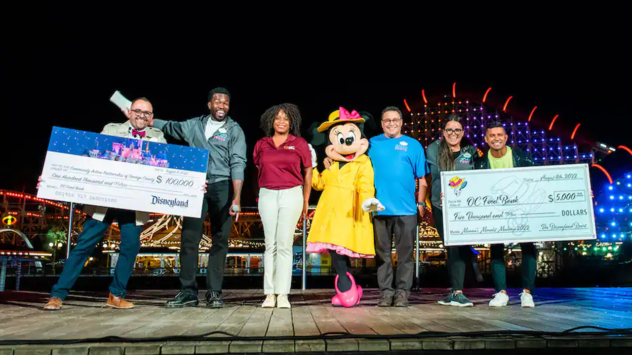Park leaders and DLR Ambassadors join Minnie onstage with checks for the Food Banks. 
