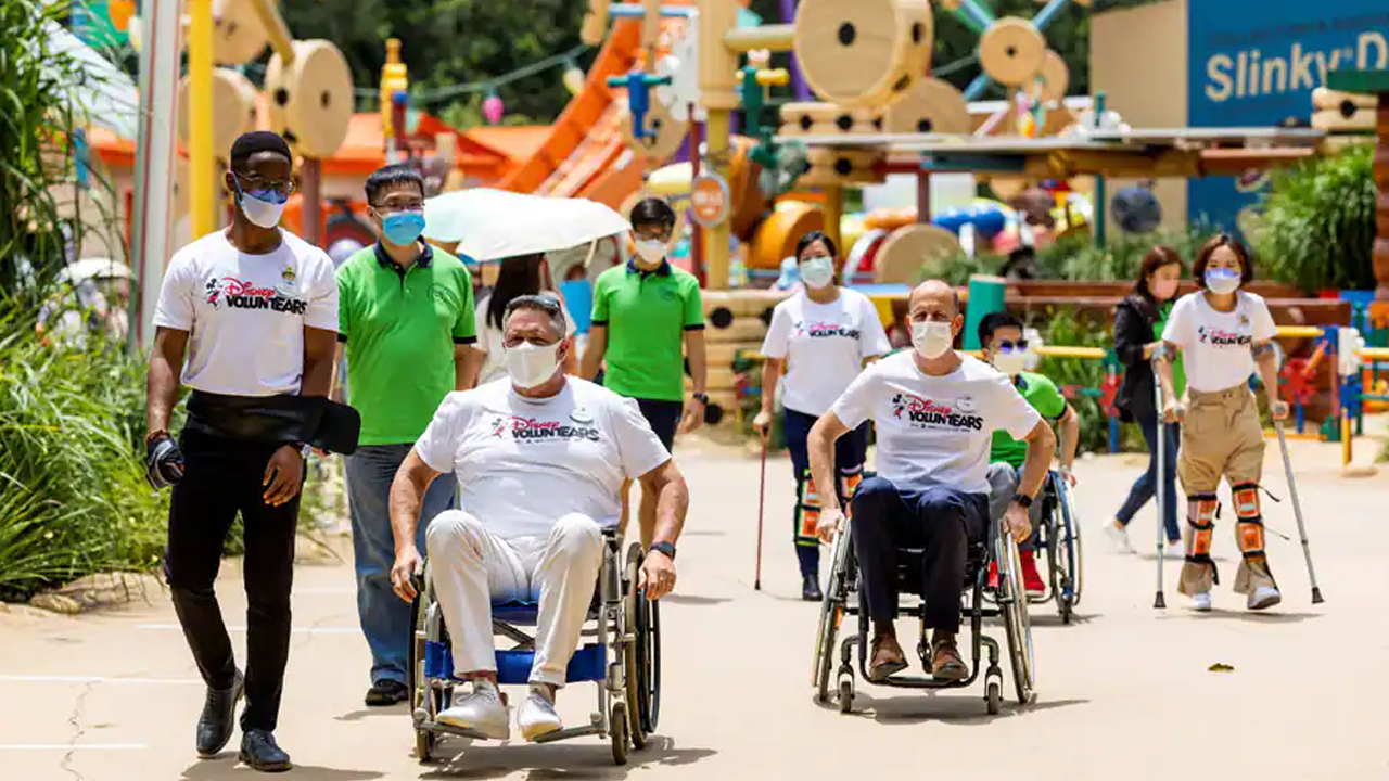 Disney Volunteers make their way though Toy Story Land. Some are using wheelchairs and crutches.
