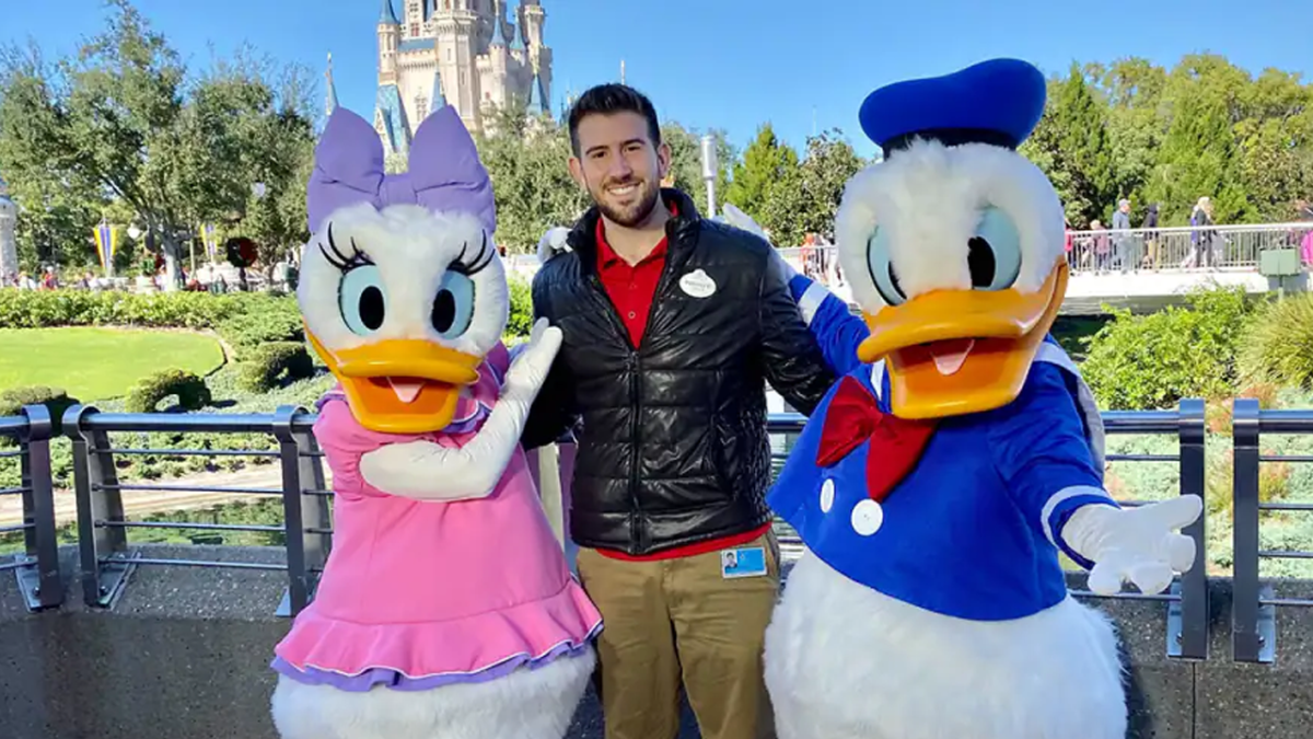 Rodolfo standing in Magic Kingdom with Daisy and Donald.