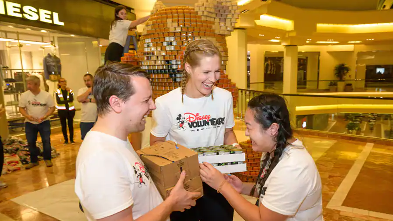 Three Cast Members laughing holding the food donations. 