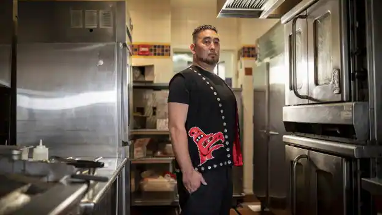 Duke standing in the kitchen in a traditional Korean vest. 