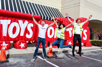 Cast Members celebrating in front of Toys for Tots blow up sign.