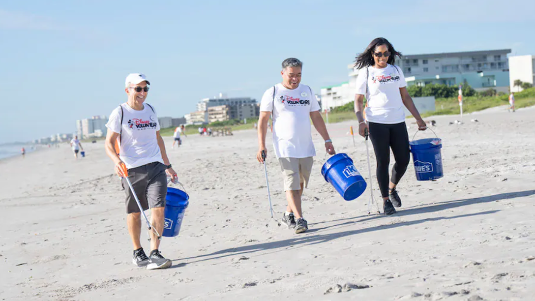 Three VoluntEARS walking on the beach with pickers and buckets.