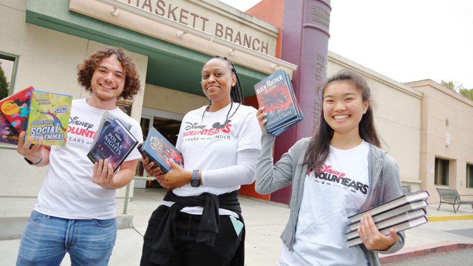 3 volunteers holding books