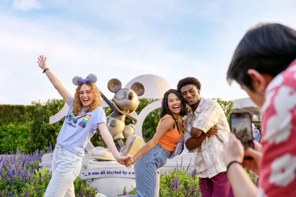 Guests taking photos in front of a statue of Mickey during Disney 100 Anniversary