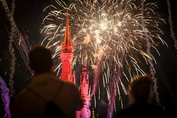 A man and a woman watch an incredible fireworks show behind the Disney castle at the Warrior Games Friends and Family Welcome Event.