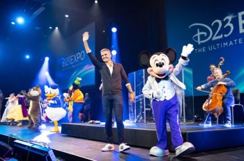 Disney Parks Chairman Josh D'Amaro on stage wit hMickey Mouse at D23 Expo.